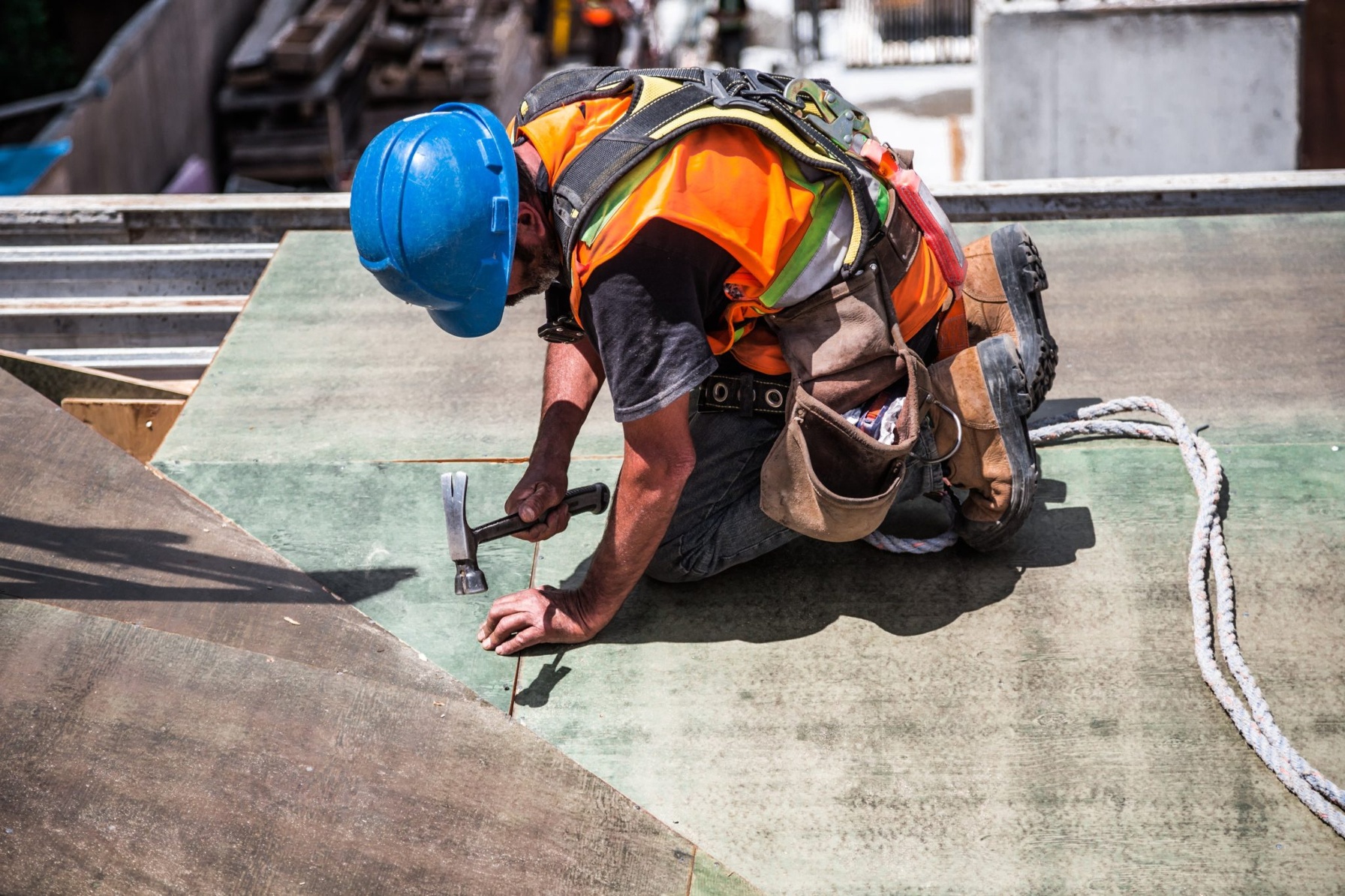 A man wearing a blue hard hat uses a hammer. It's crucial to properly classify a worker before hiring to avoid costly penalties, back taxes, and potential litigation.